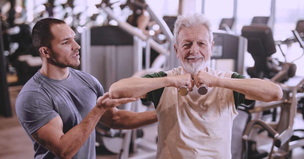 Personal trainer aplicando treinamento em aluno da terceira idade